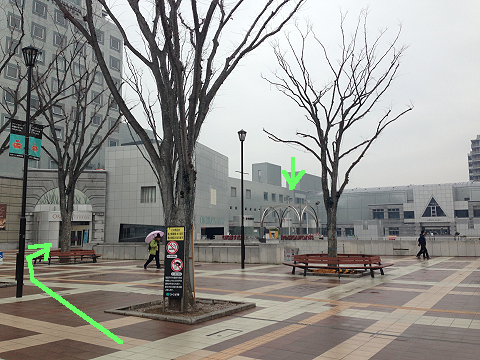 階段を上りきりました。左手に進みます。左手にある大きな建物がセンタービルです。中央の緑の矢印が会場の入り口です。 左手に進んでいきます。 When you go up the steps, the Tsukuba Center Building will appear. The green arrow on a building shows the entrance of the meeting venue. Go left side.